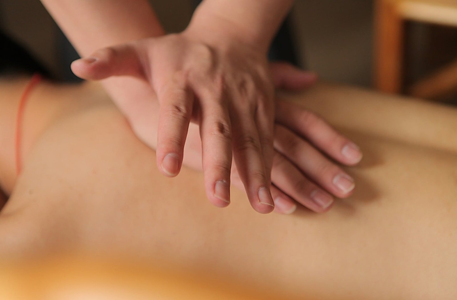 Les mains de la massothérapeute posées sur le dos d'une cliente